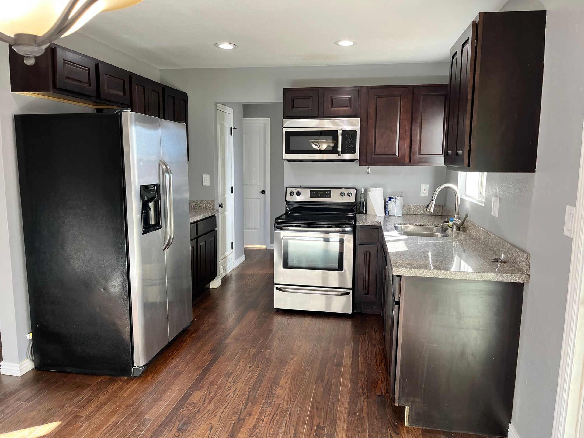 A kitchen with a refrigerator , stove , microwave and sink.