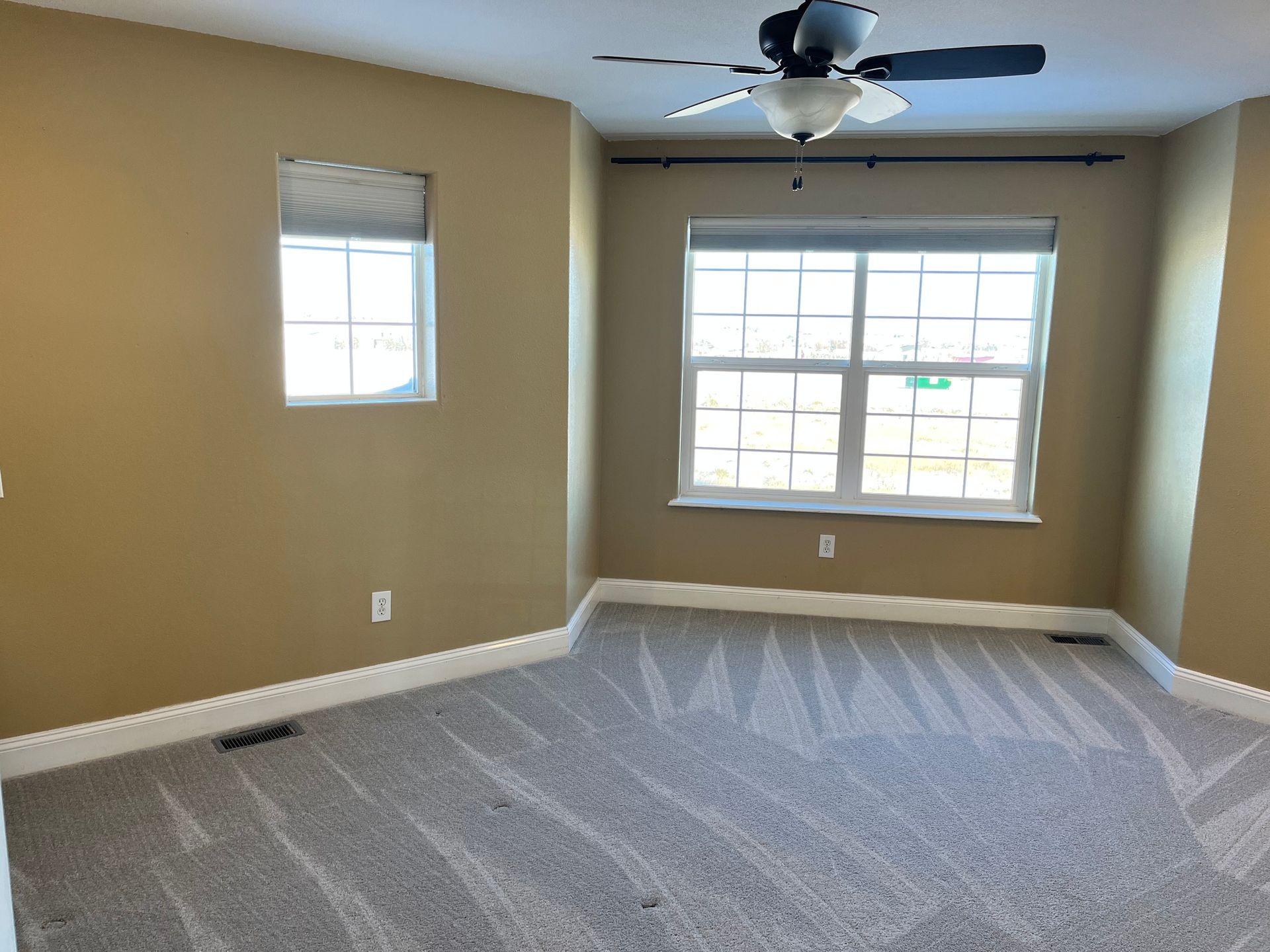 An empty bedroom with a ceiling fan and a window.