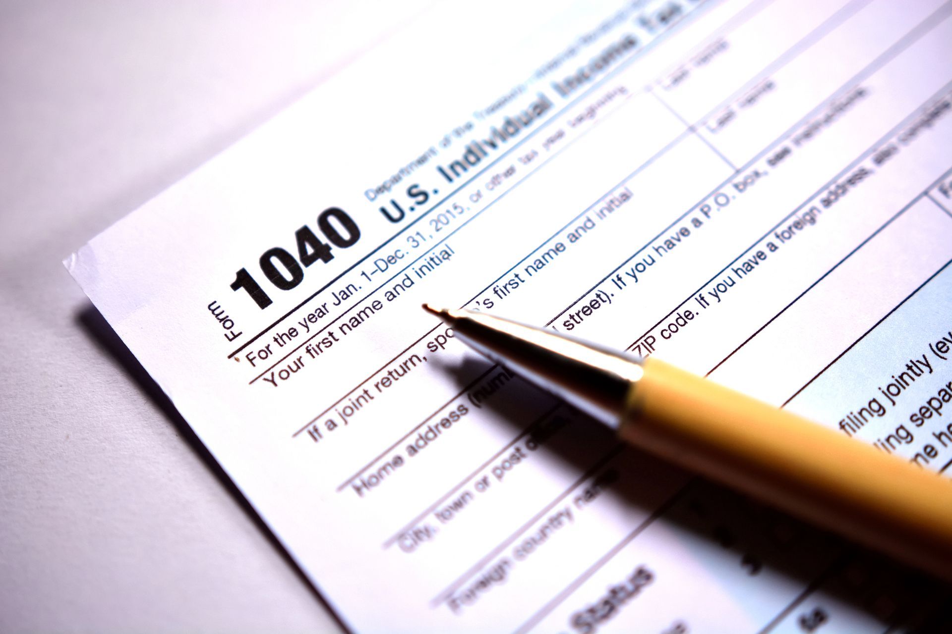 Blank form 1040 lying on a desk with a pen on the tax return