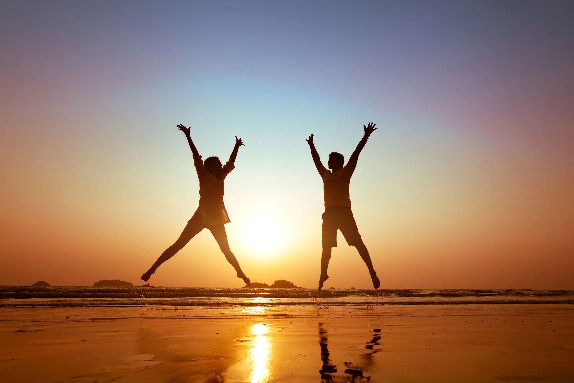 Freedom. Two people jumping for joy on a beach.