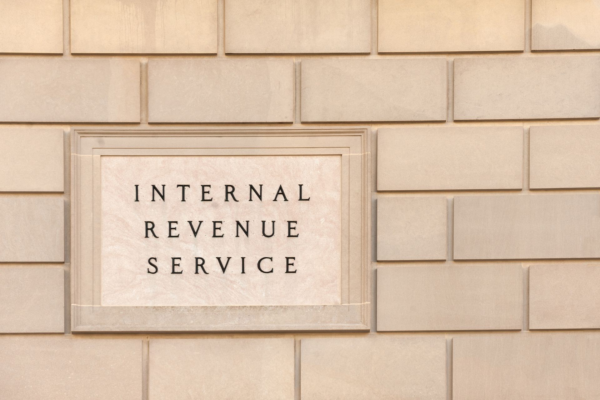 IRS sign on a beige brick IRS building wall.