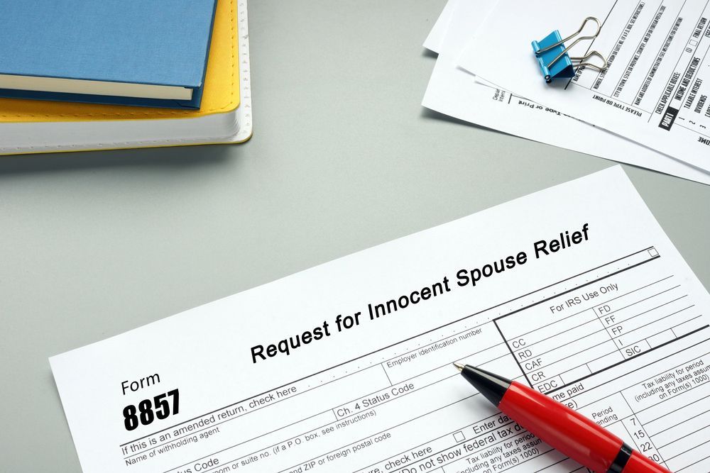 Innocent spouse relief form 8857 lying on desk with a red pen and notebook