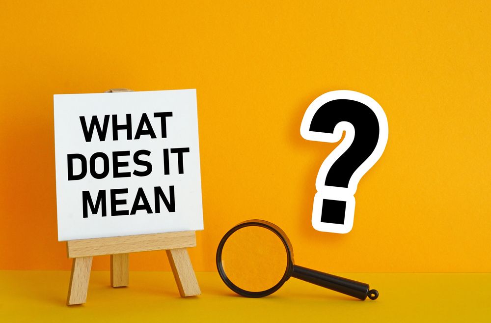 WHAT DOES IT MEAN typed on a white poster that is on an easel with magnifying glass