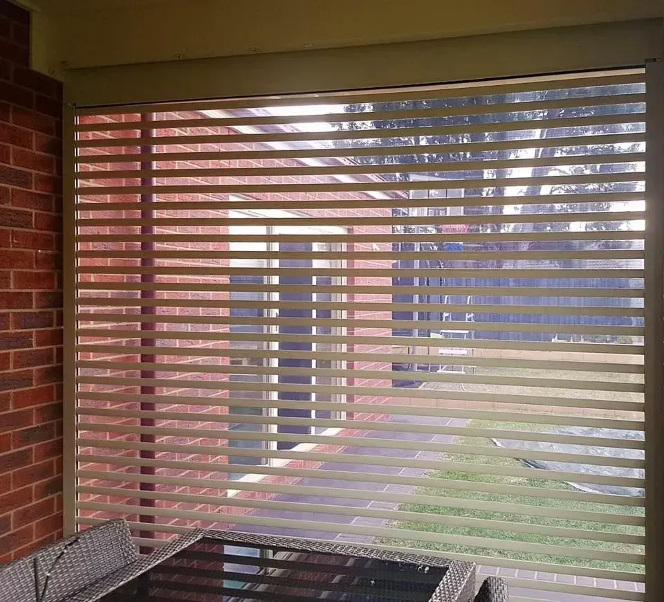 A patio with a table and chairs in front of a window with blinds — LT Shutters in Wollongong, NSW