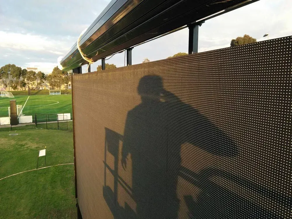 A shadow of a person is cast on a fence in a park — LT Shutters in Huskisson, NSW