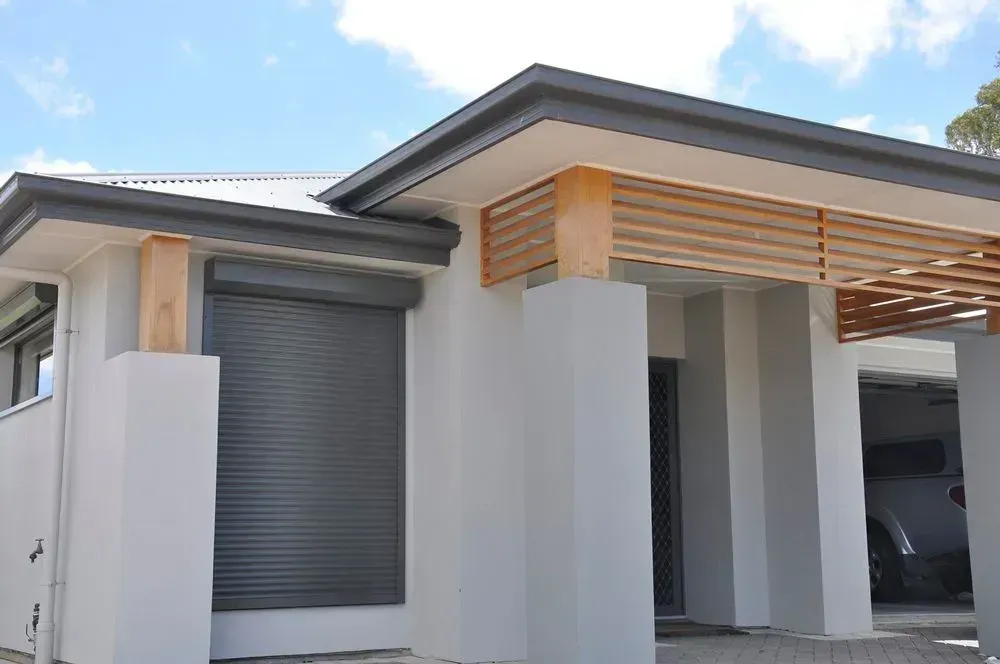 A white house with black shutters on the windows is under construction — LT Shutters in Dapto, NSW