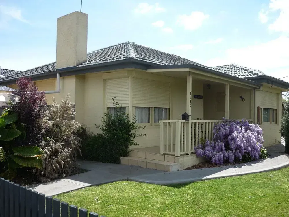 A house with a porch and purple flowers in front of it — LT Shutters in Port Kembla, NSW