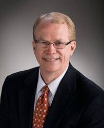 A man in a suit and tie is smiling for the camera.