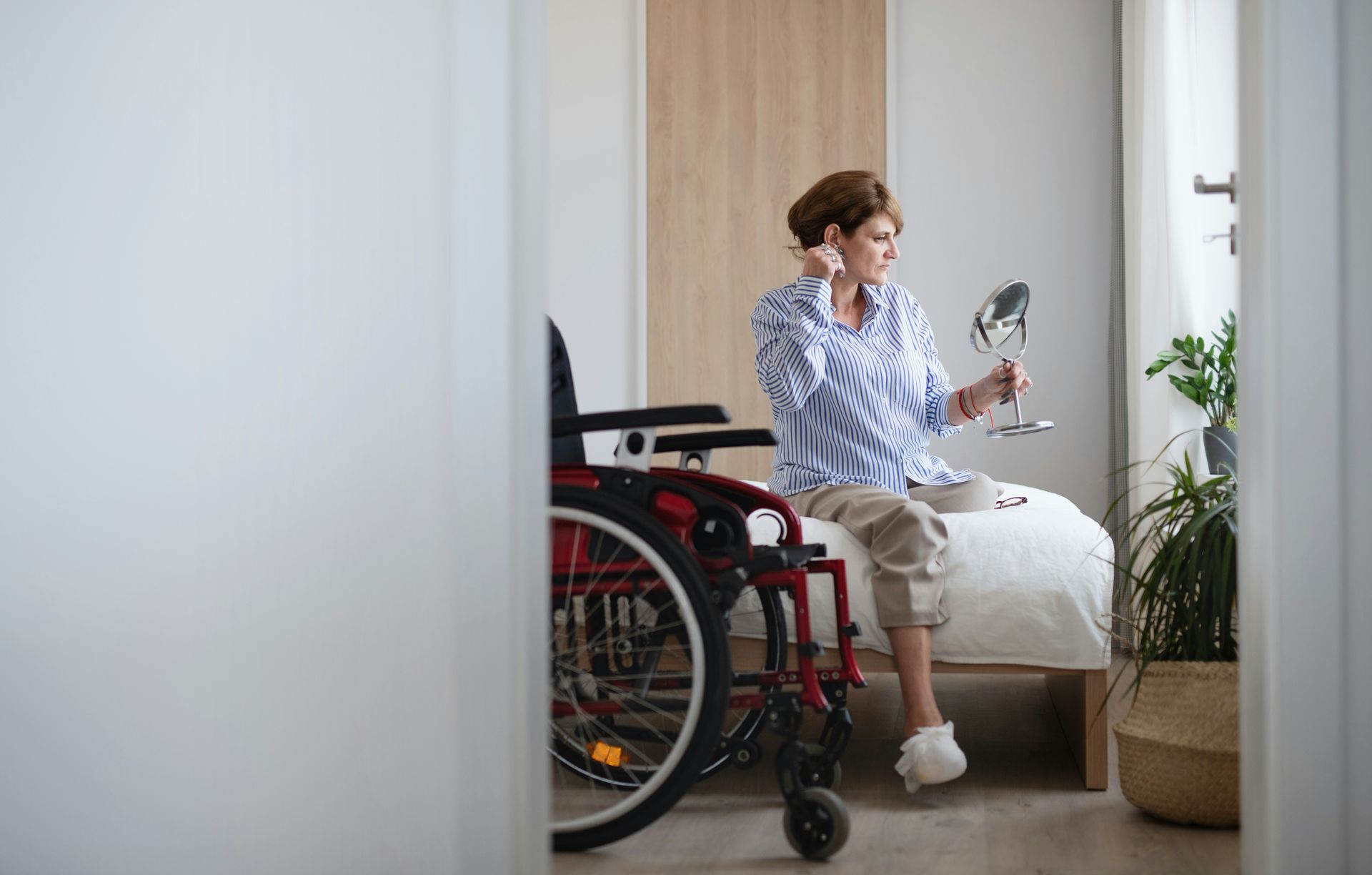 A woman in a wheelchair is sitting on a bed talking on a cell phone.