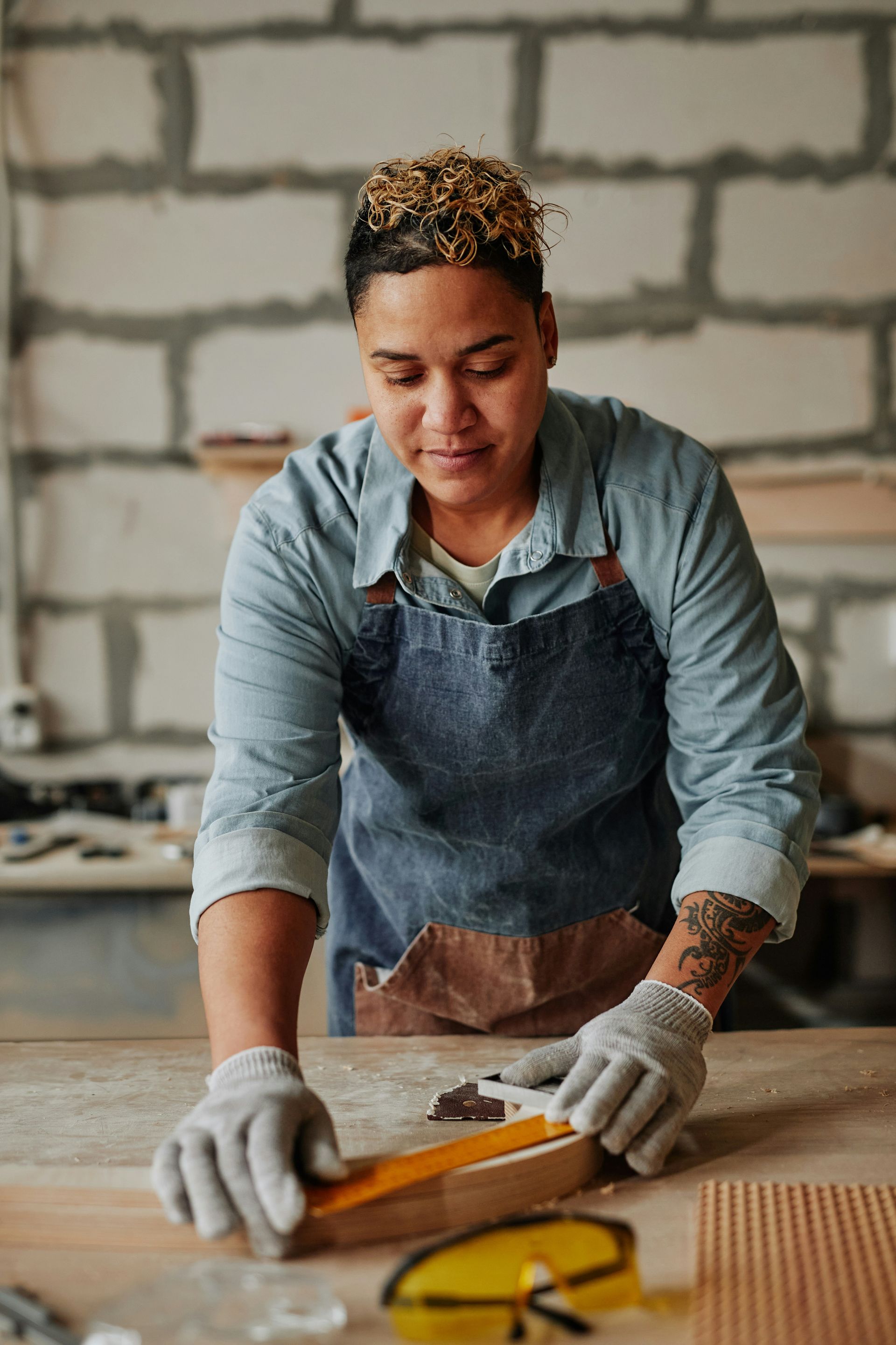 A woman is working on a piece of wood in a workshop.