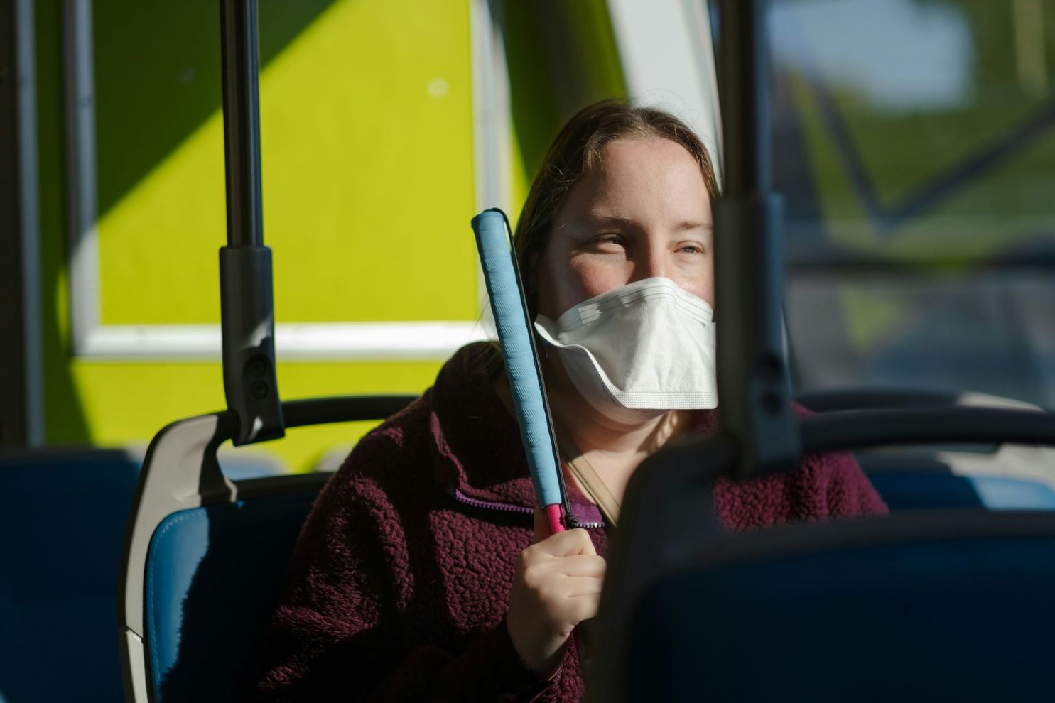 A woman wearing a mask is sitting on a bus.