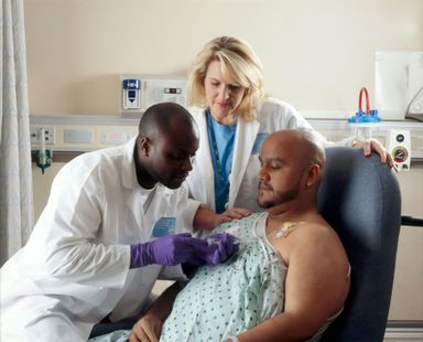 A man in a hospital gown is being examined by two doctors