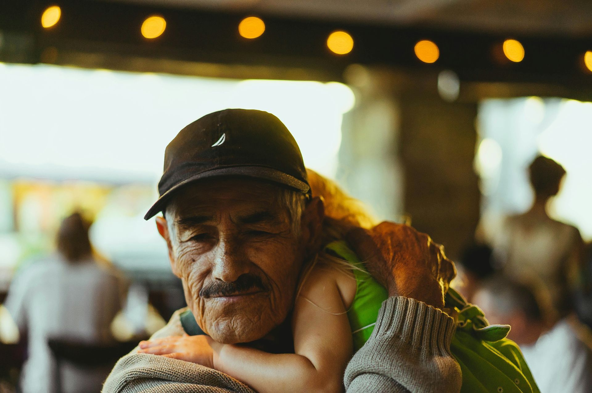 An older man is carrying a little girl on his shoulders.