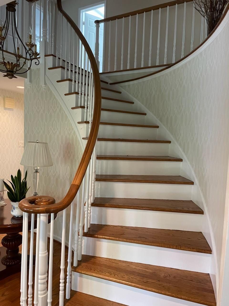 A curved staircase with white railings and wooden steps in a living room.