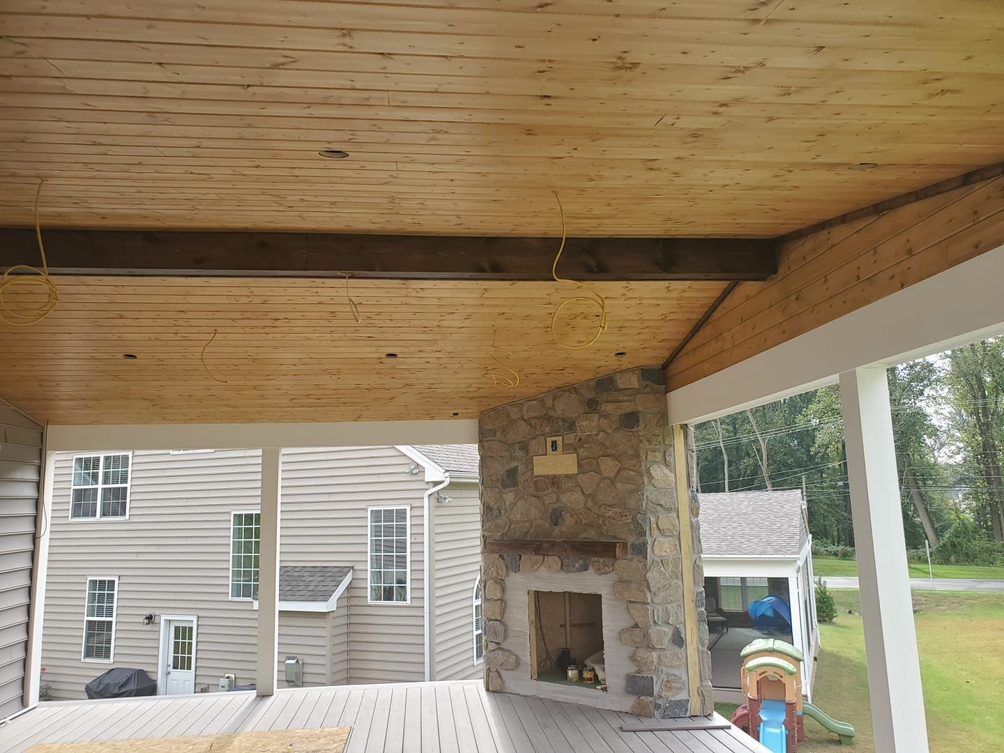 A wooden deck with a fireplace and a house in the background