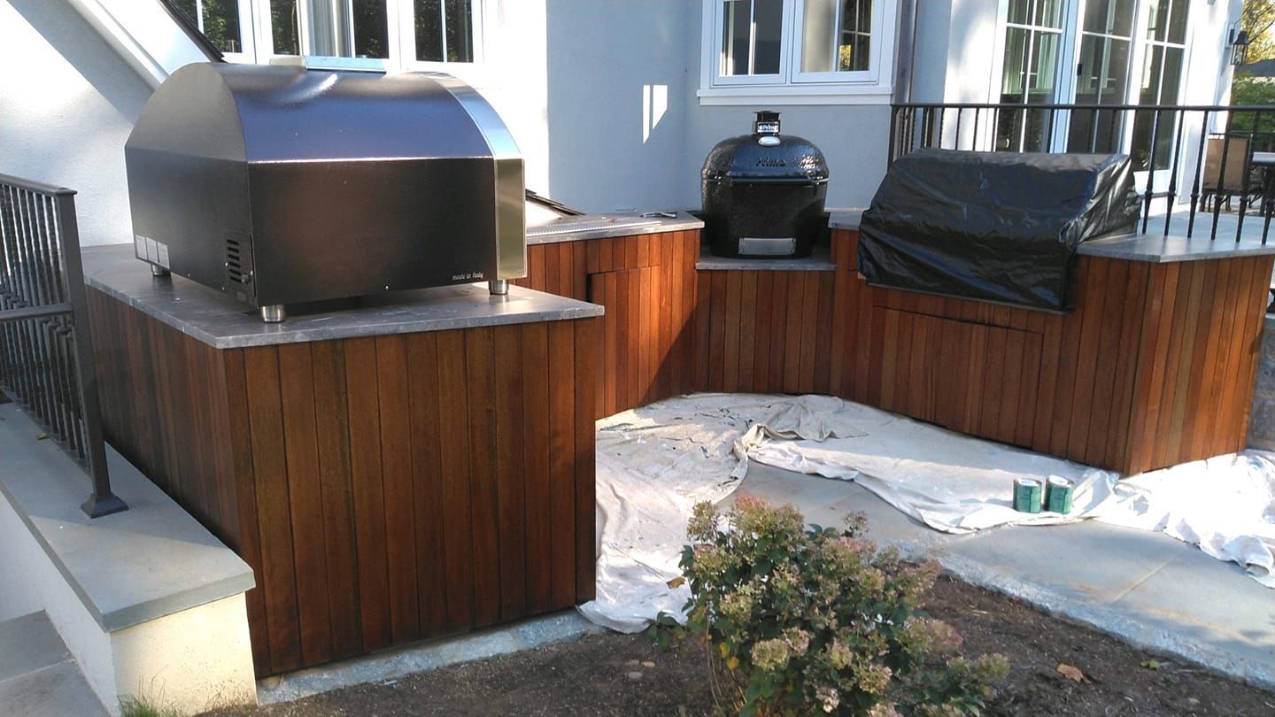 A grill is sitting on top of a wooden table in front of a house.
