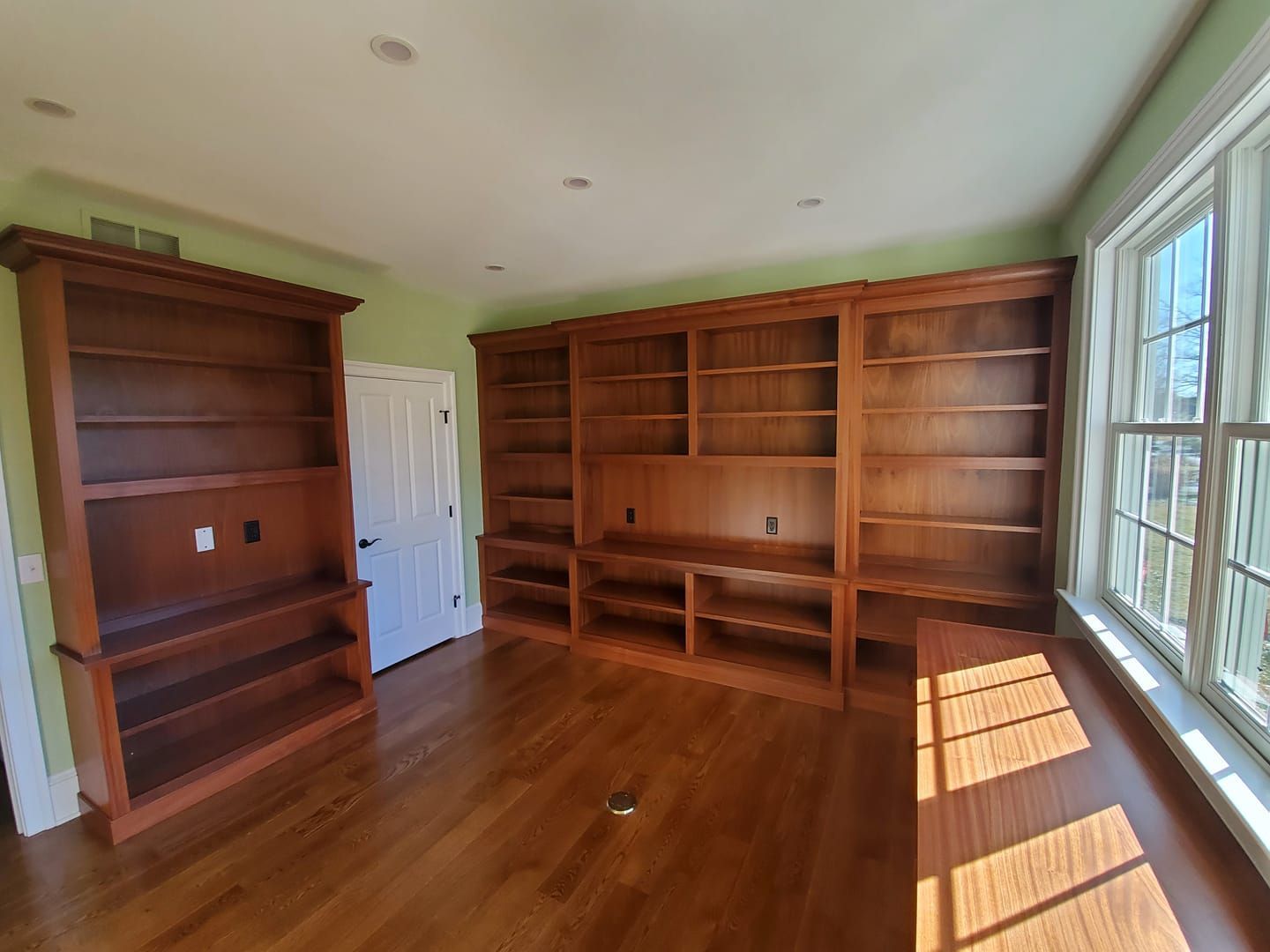 A large empty room with wooden shelves and a desk.