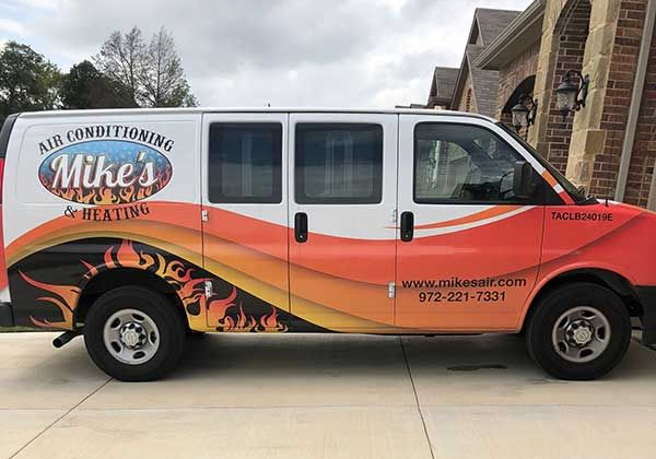 White and orange Mike’s Air Conditioning service van parked outside a brick building