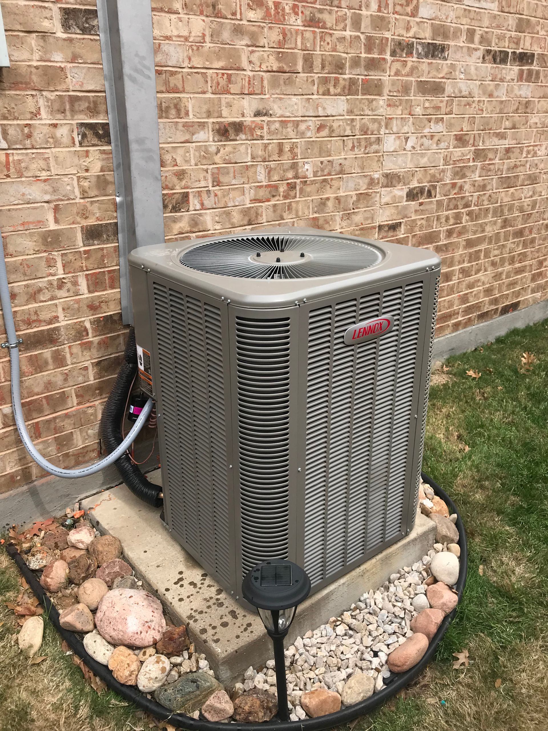 Person using a torch to repair an outdoor HVAC unit with tools on the ground