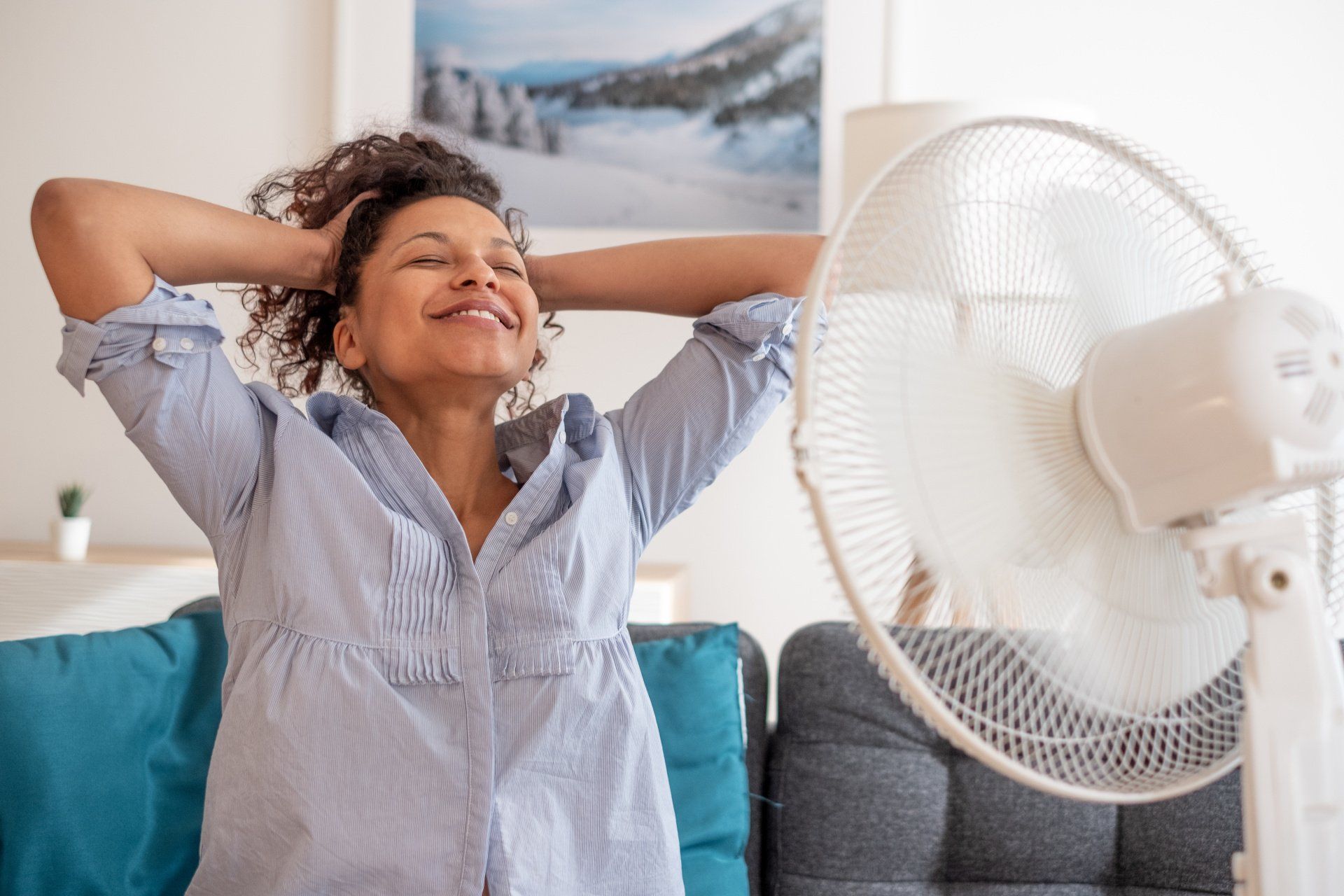 black woman in front of fan cooling off at home