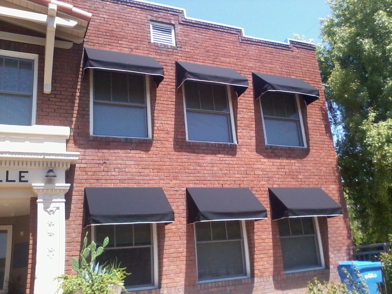 red brick building with AZ Awning dark covered awnings covering windows
