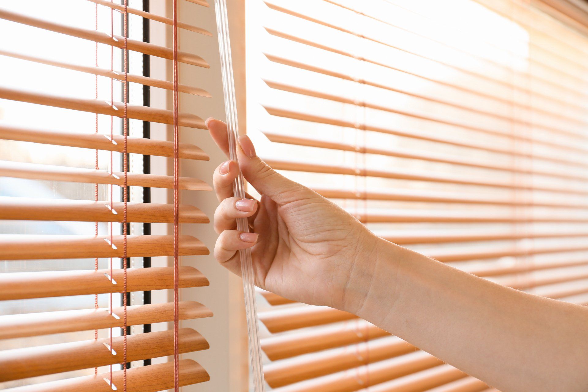 woman closing blinds on window