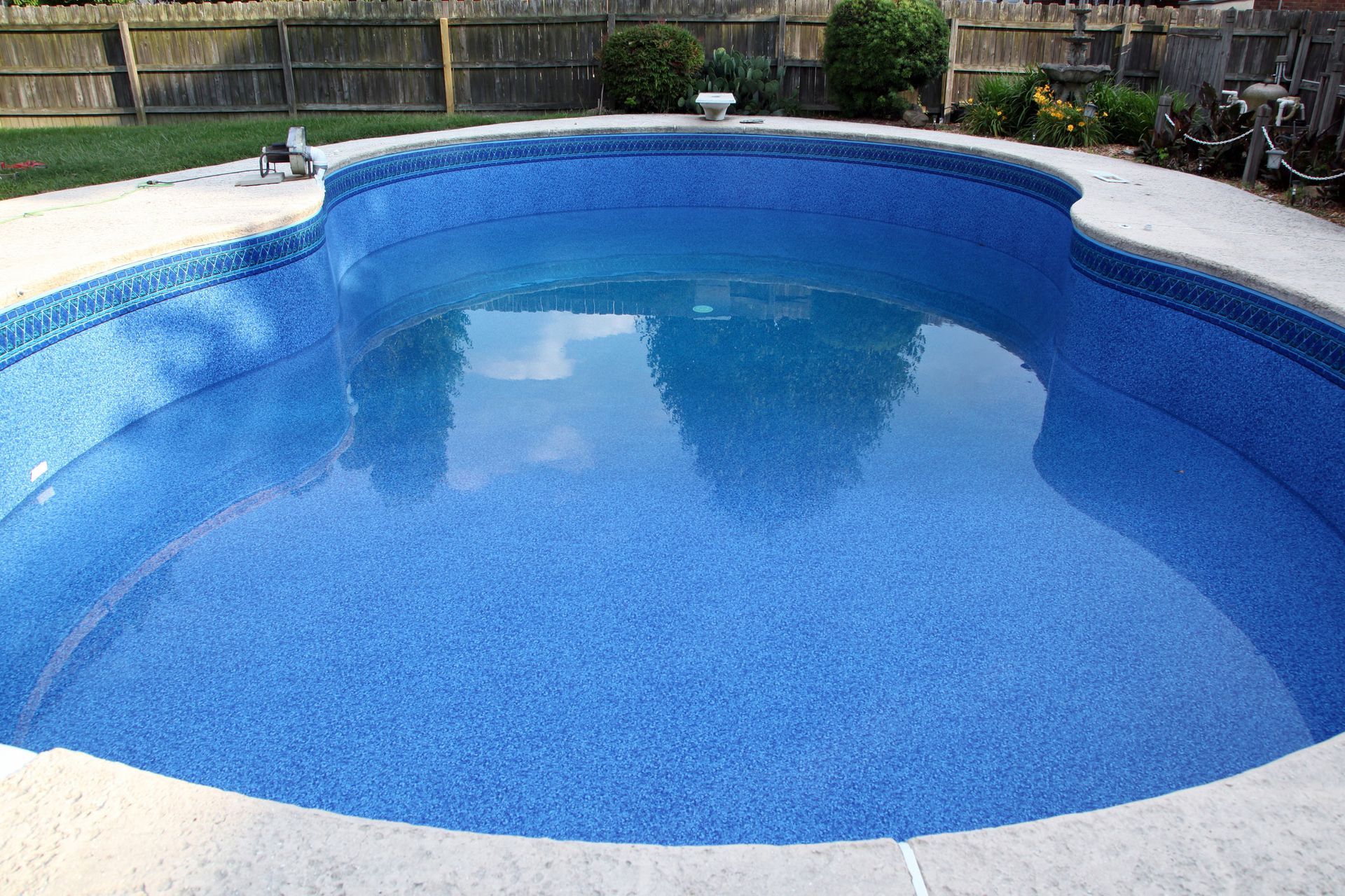 A large swimming pool filled with blue water in a backyard. A large swimming pool filled with blue water in a backyard.