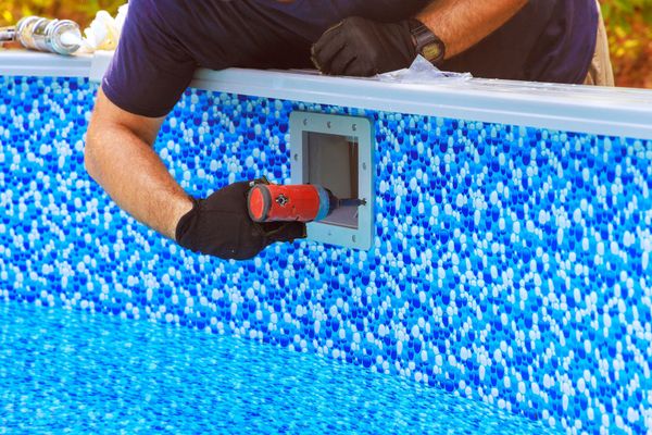 A man is working on a swimming pool with a drill.