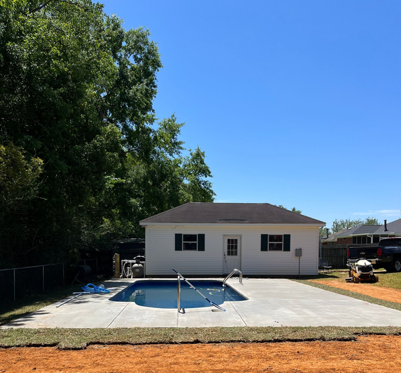 A man is cleaning a swimming pool with a hose. A man is cleaning a swimming pool with a hose.