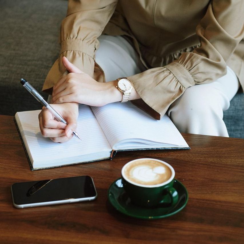 Frau schreibt in ihr Notizbuch – Moment der Reflexion, Planung und inneren Klarheit. Frauencoaching bei Anna Cisek