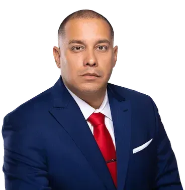 A man in a blue suit and red tie is sitting in front of a white background.