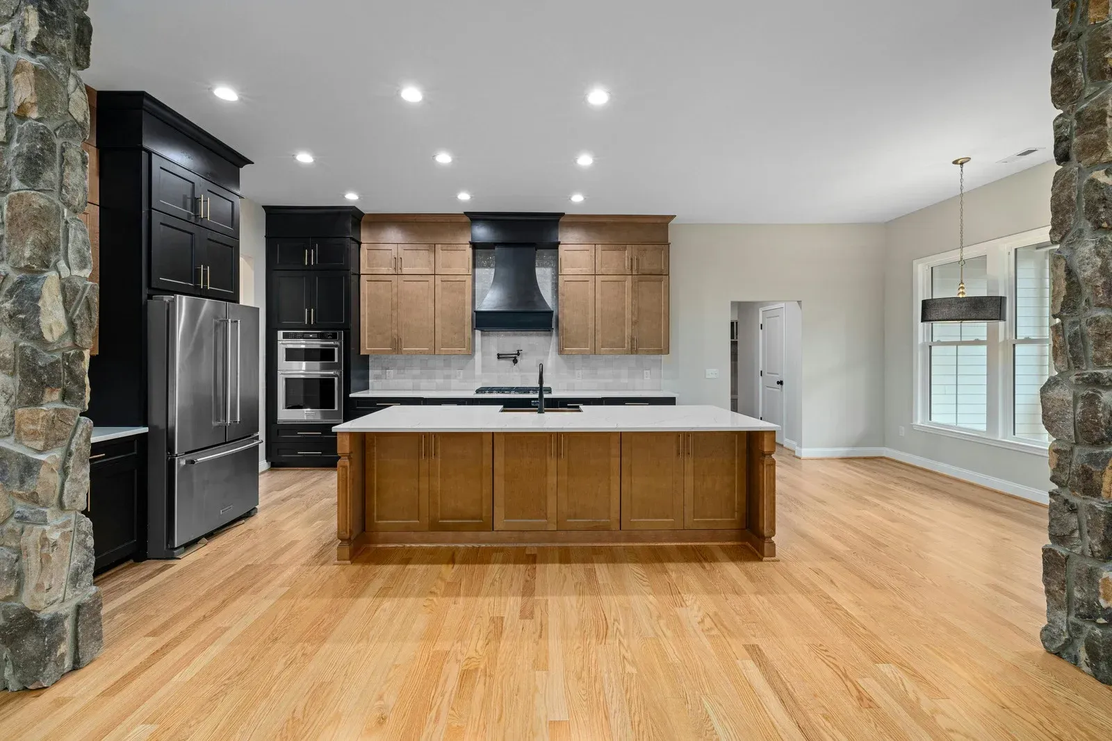 A bright kitchen featuring a wooden island, light wood flooring, and a mix of dark and natural wood cabinetry.