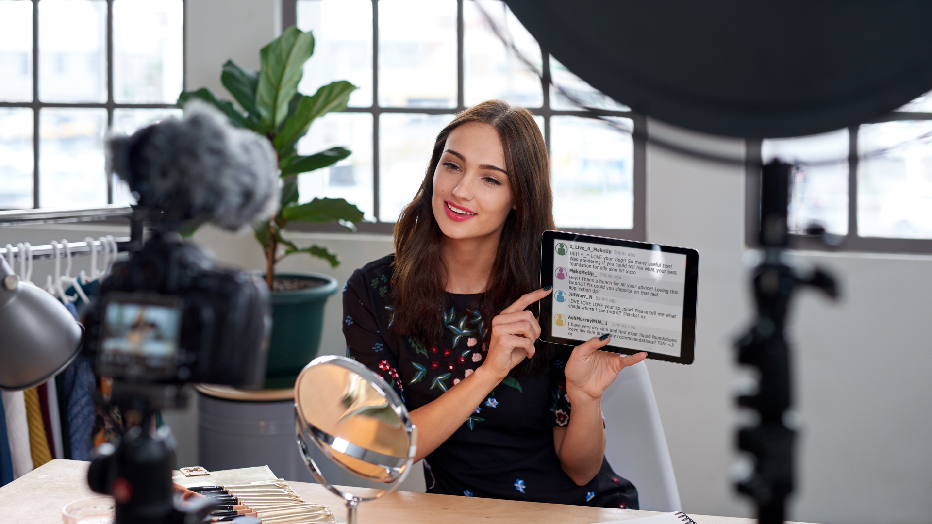 A smartphone mounted on a ring light, possibly for recording. A person is slightly blurred in the background.