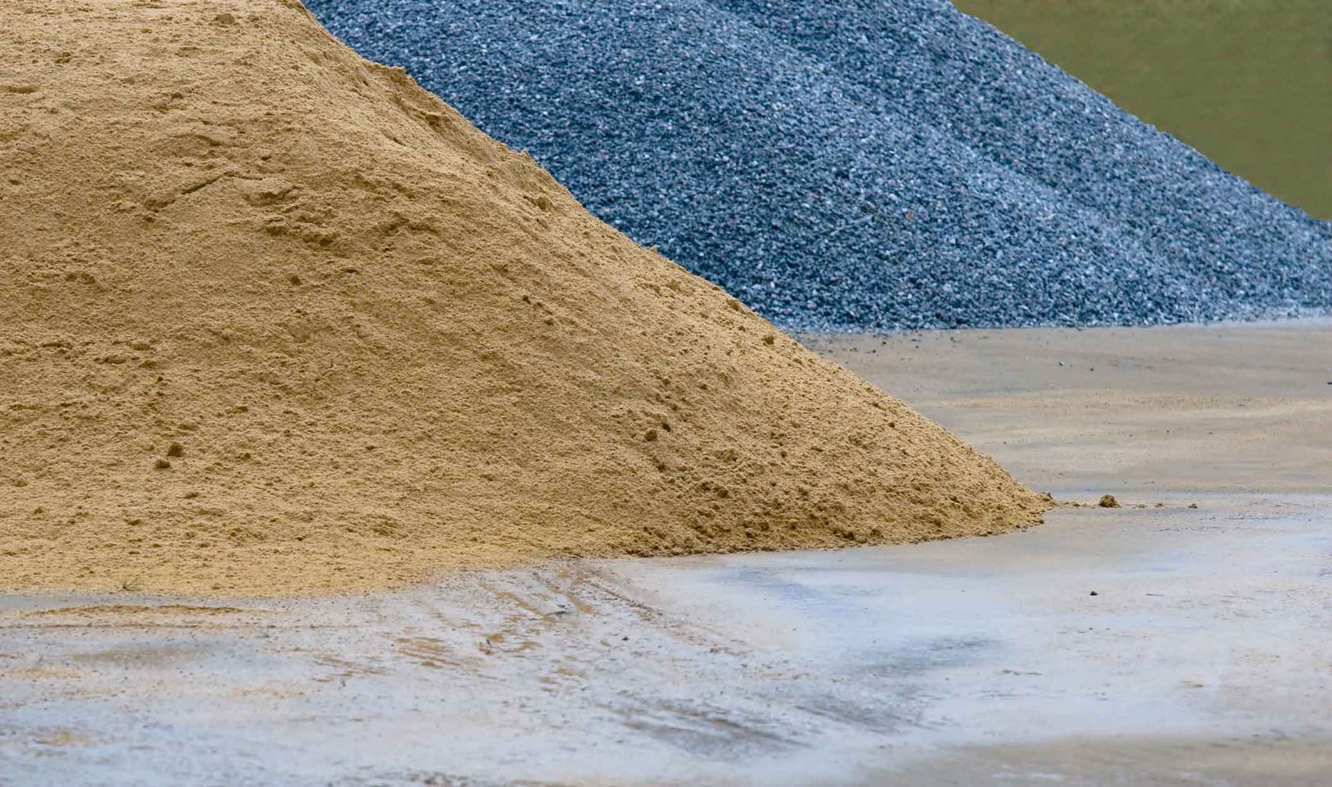 Piles of tan and blue gravel on a concrete surface