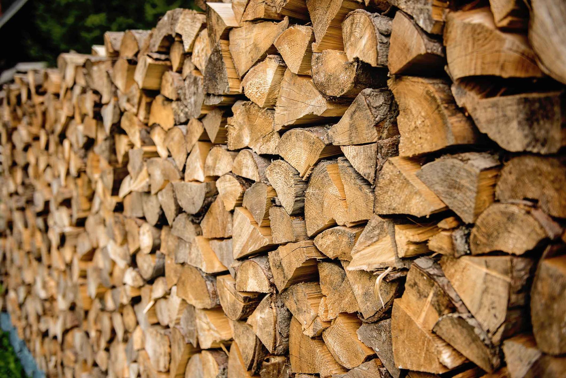 Stacked split firewood logs in a neat pile, with rough bark and cut ends visible.