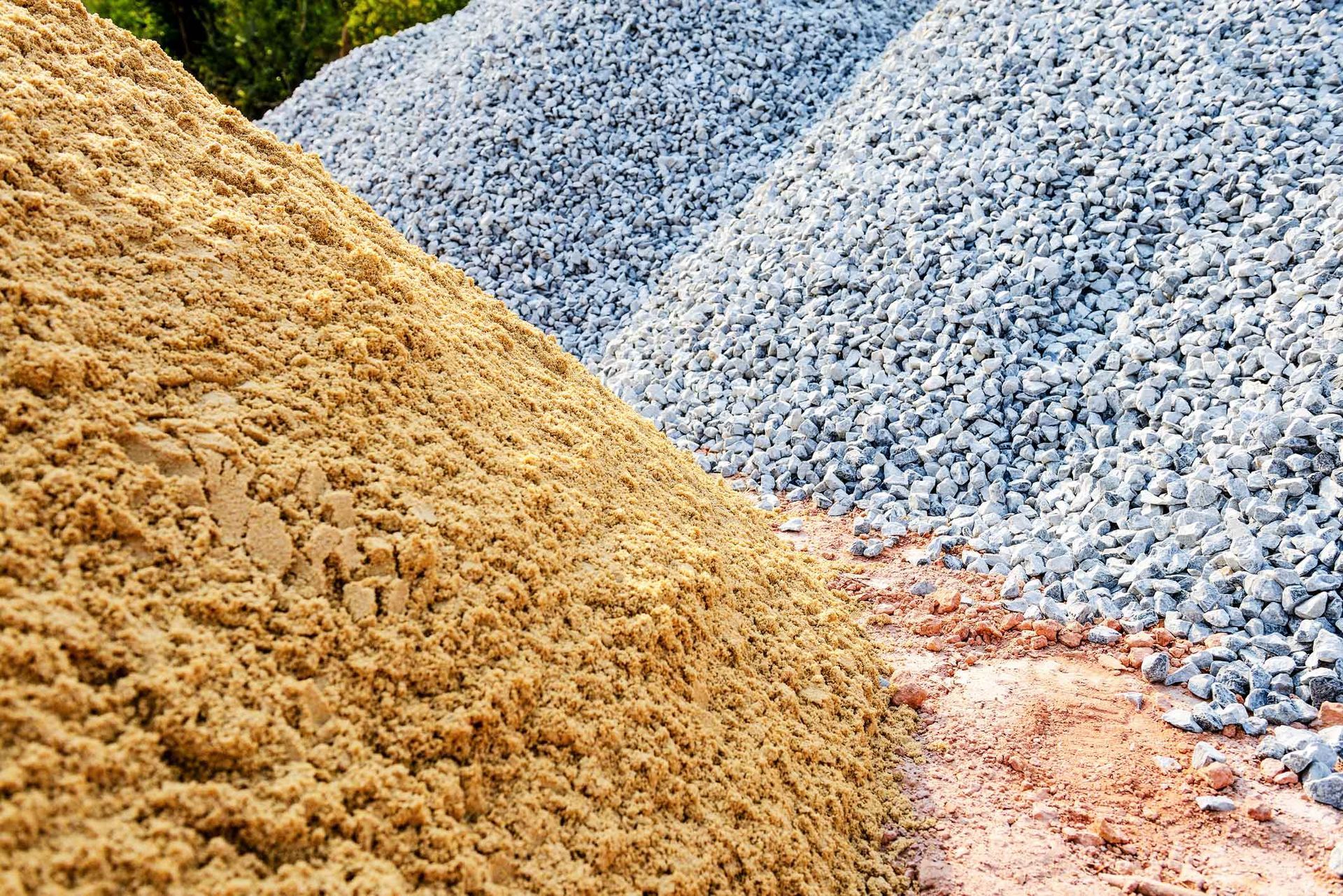 Piles of tan, blue, and pink gravel stacked outdoors