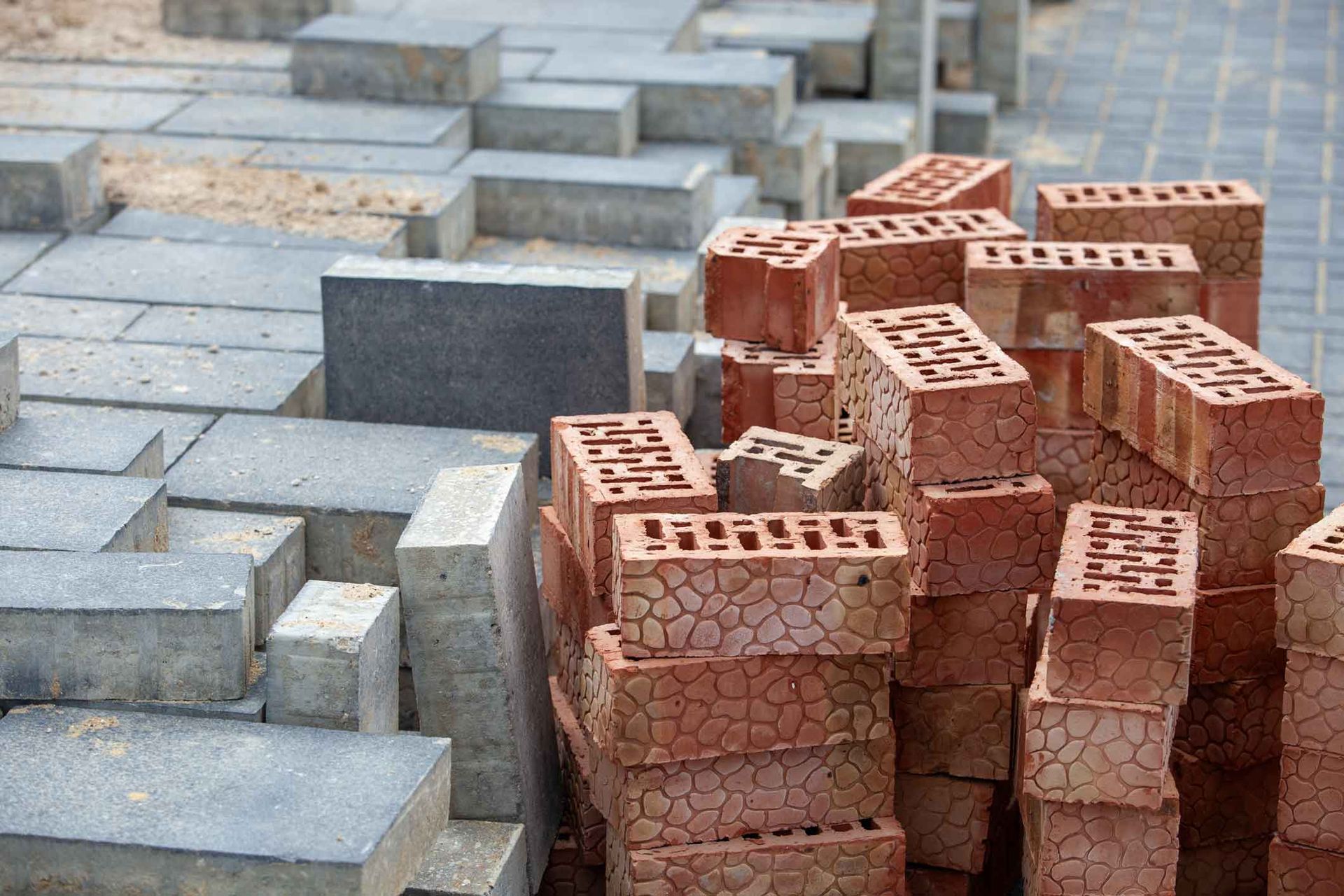 Stacks of gray concrete blocks beside a pile of red bricks on a construction site Stacks of gray concrete blocks beside a pile of red bricks on a construction site