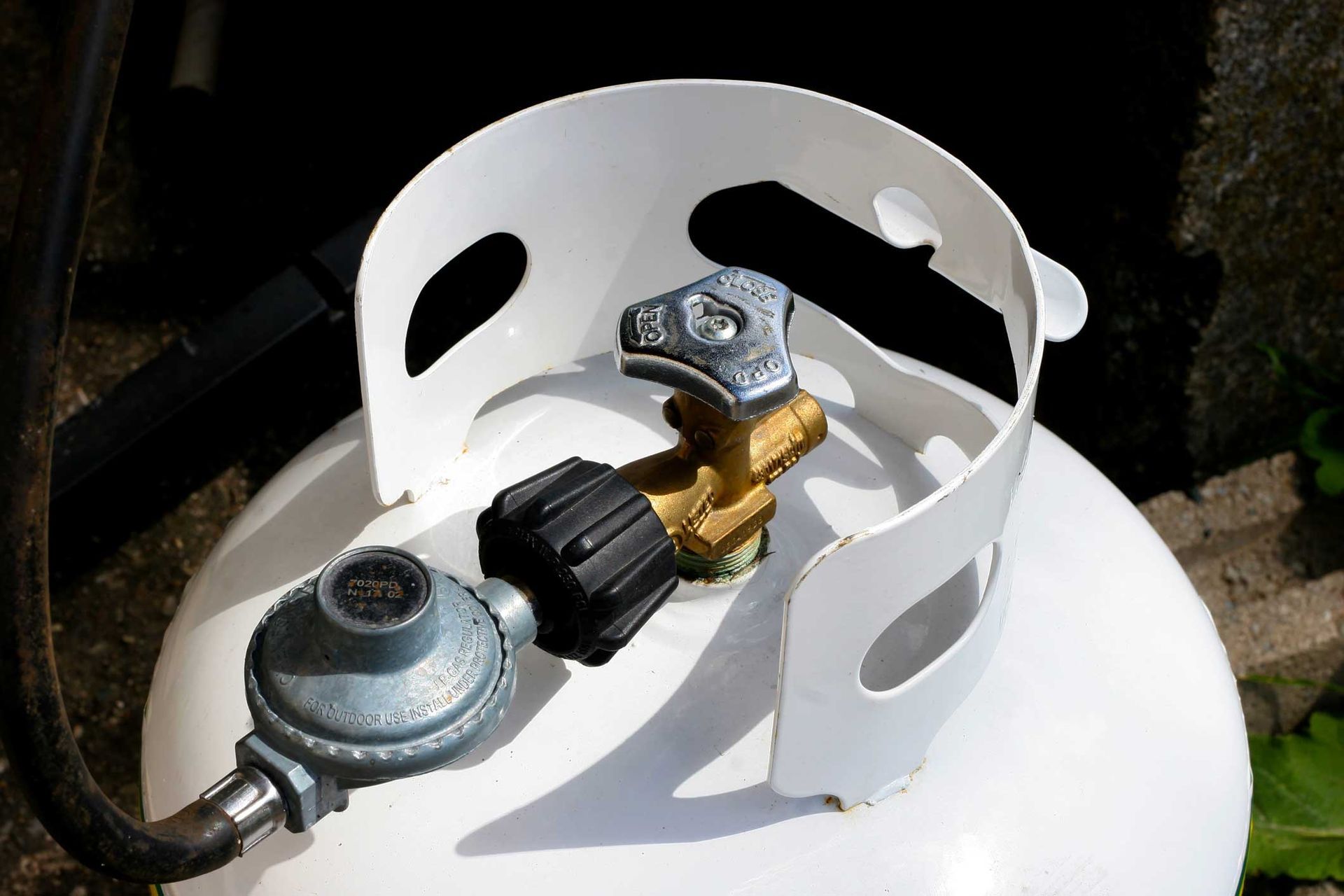 Propane tank valve with pressure regulator and hose connection on a white cylinder