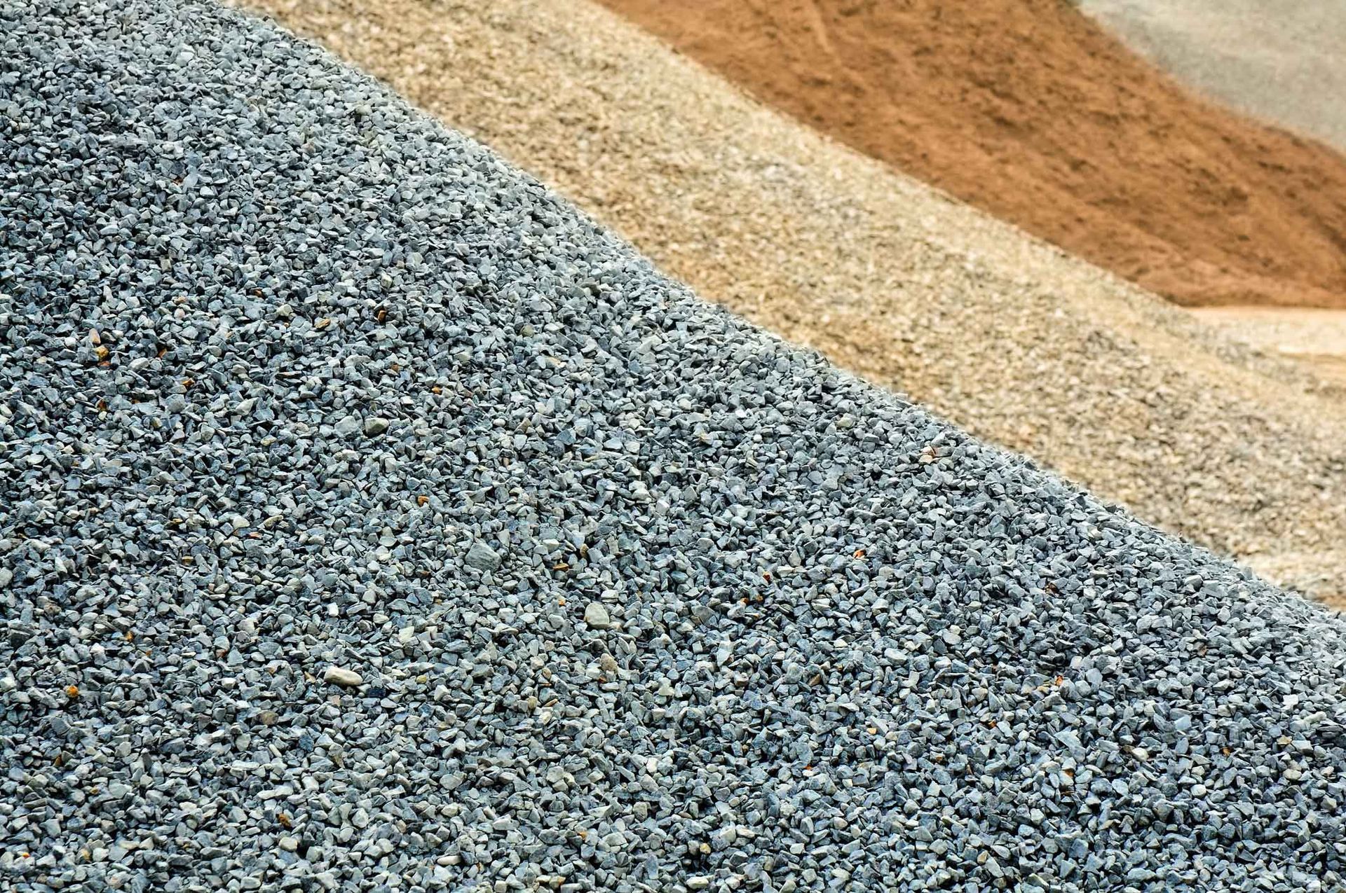 Piles of gravel in gray, tan, and rust tones stacked in sloping layers