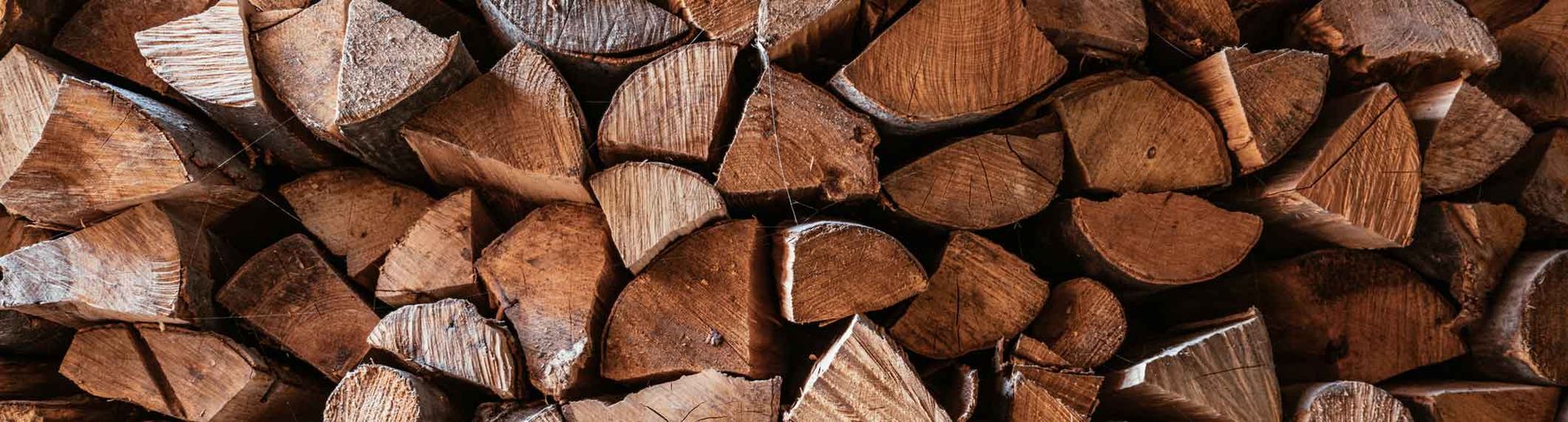 Pile of cut brown firewood logs stacked tightly together