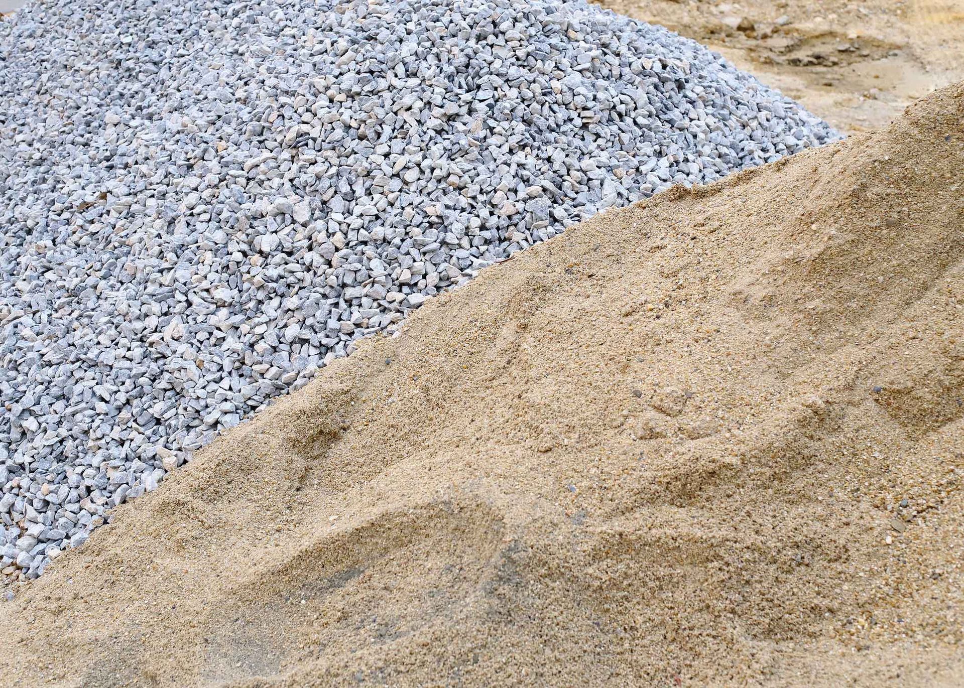 Pile of gray gravel and tan sand at a construction site