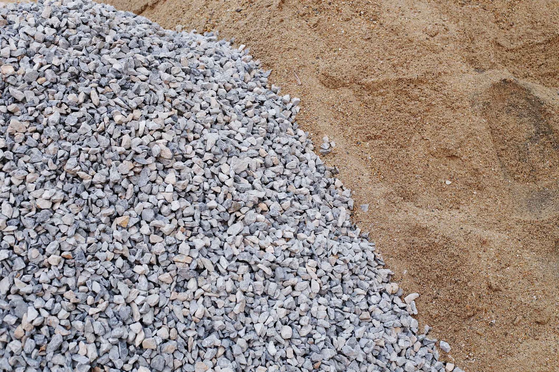 Pile of gray gravel beside a mound of tan sand