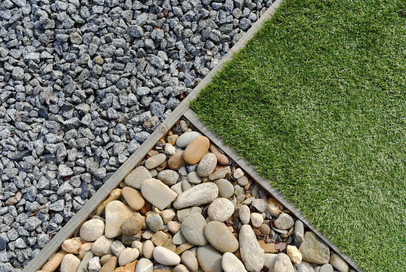 Three triangular sections of gravel, pebbles, and green grass separated by stone borders