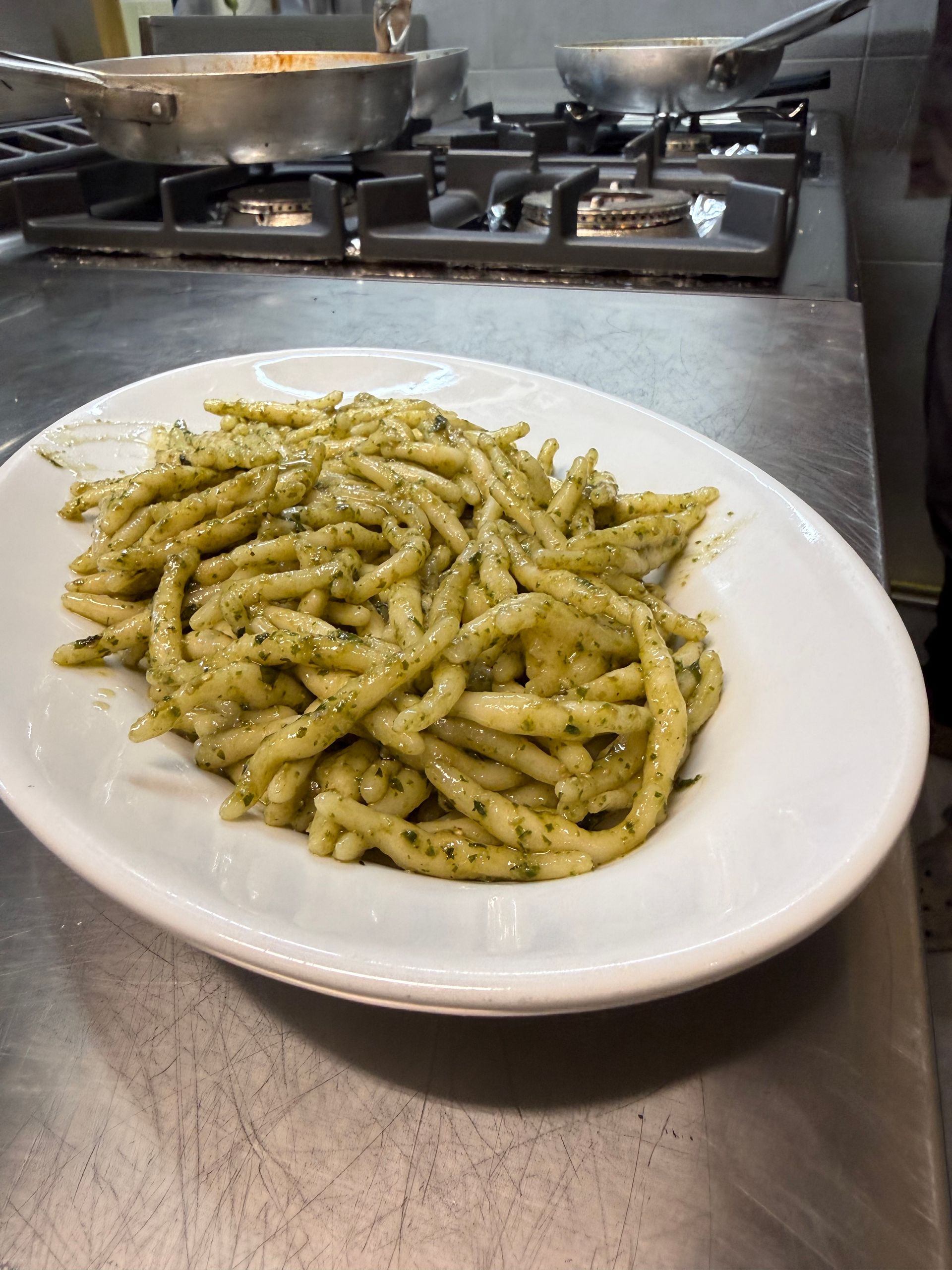 Piatto di pasta in un piatto ovale bianco, su una superficie in acciaio inossidabile, in cucina.