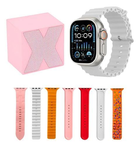 Un reloj inteligente con una correa blanca, varias correas de colores y un altavoz rosa.