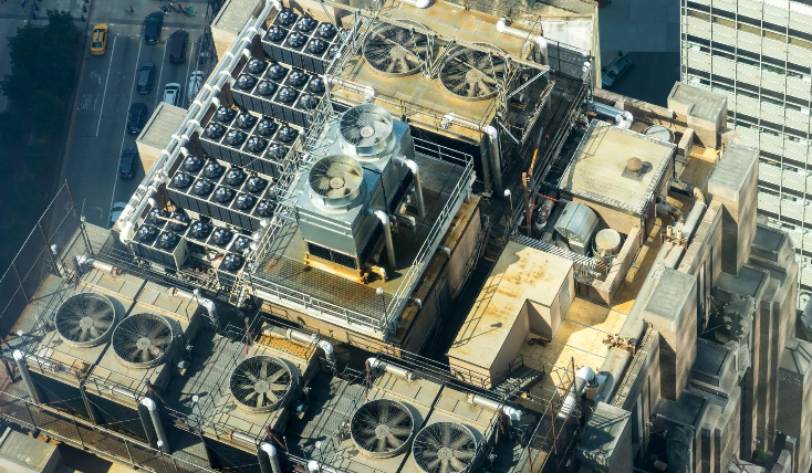 Rooftop of a building with numerous HVAC units and fans, viewed from above.