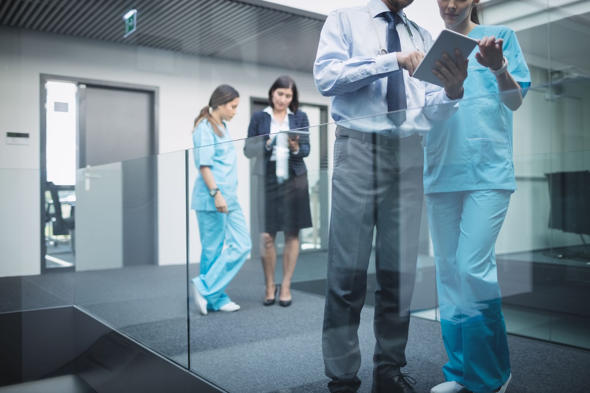 Doctors standing in hospital corridor using portable healthcare technology