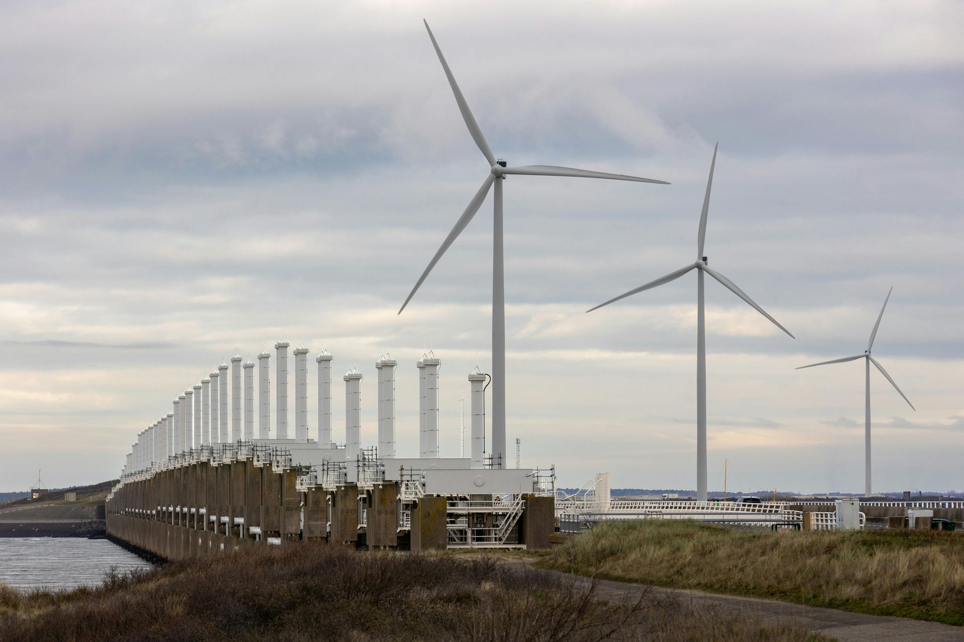 Three wind turbines stand next to the Oosterscheldekering storm surge barrier. Sky-Walker