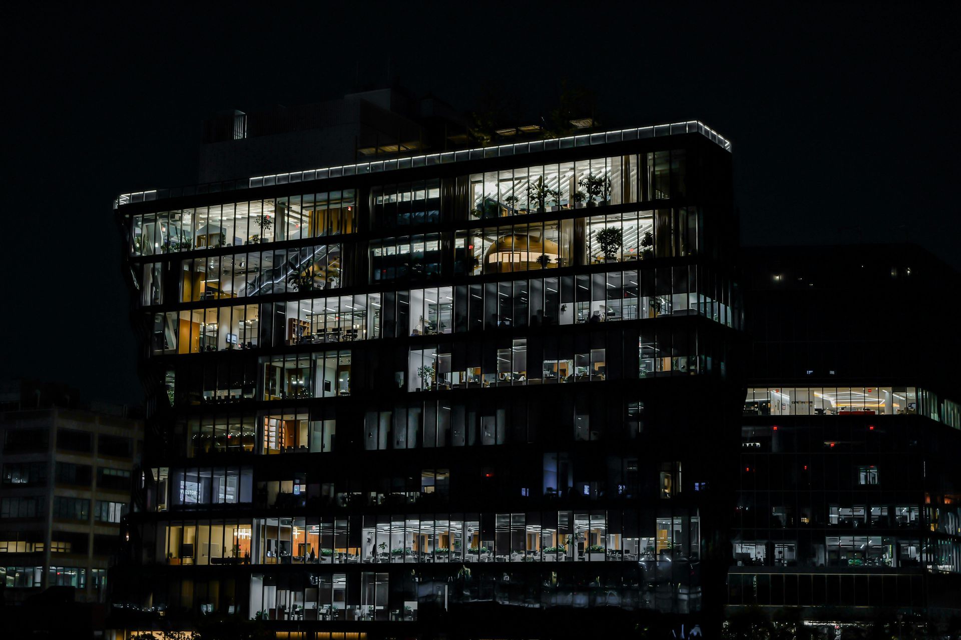 Illuminated office building at night with many lit windows against a dark sky