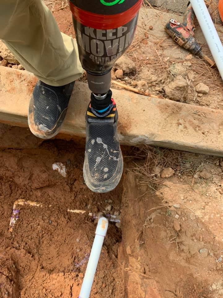 A person is using a drill to fix a pipe in the ground.